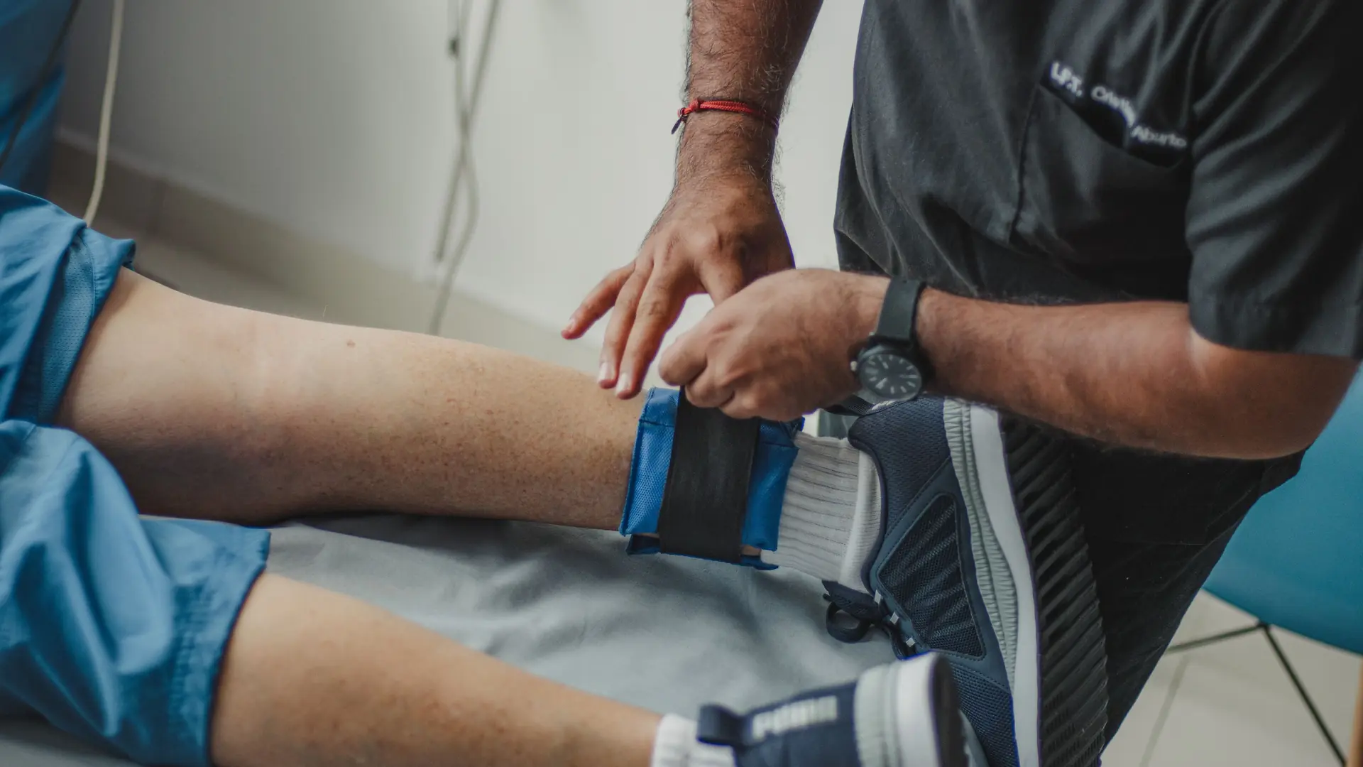 A physiotherapist fits a strap around a patient’s ankle