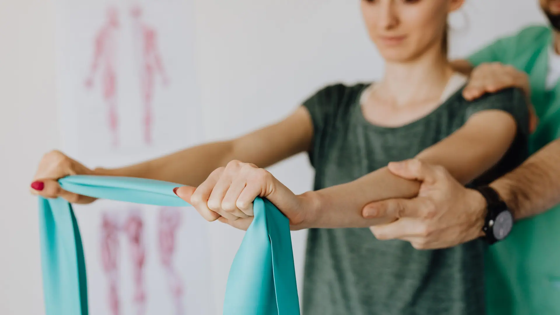 A physiotherapist guides a patient’s arm with a resistance band
