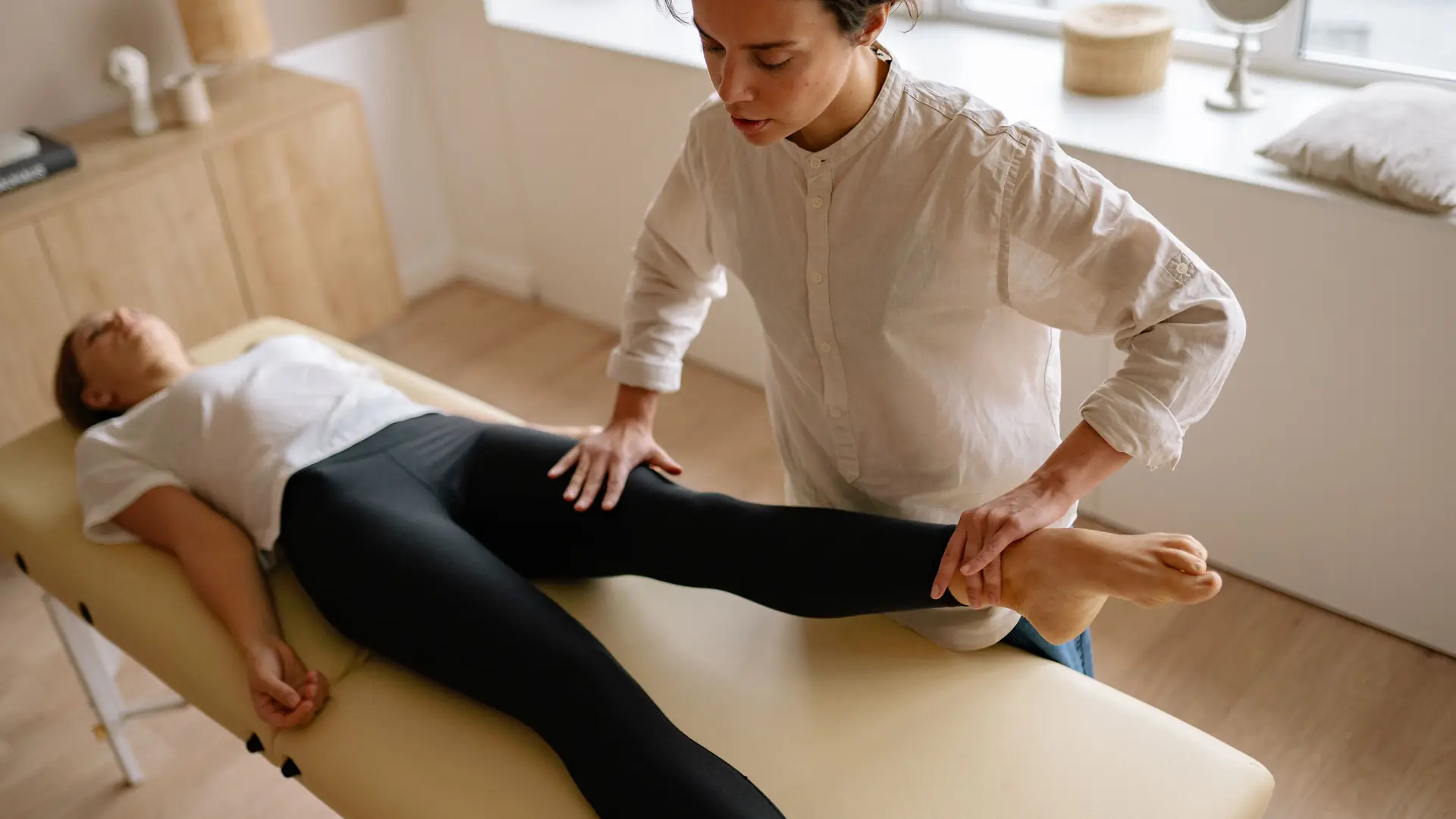 A physiotherapist works on a patient in a quiet white room