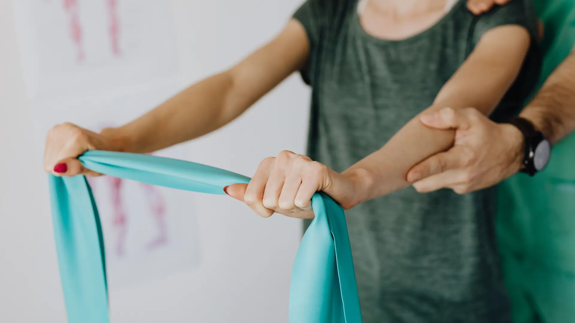 A physiotherapist guides a patient’s hands on a resistance band