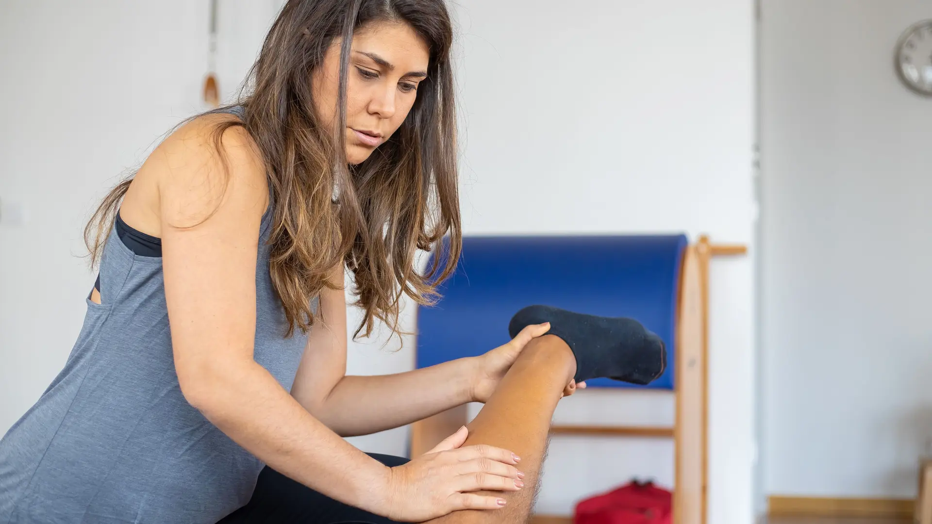 A physiotherapist holds a patient’s knee during treatment