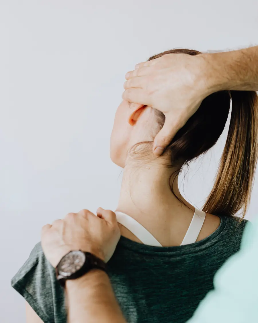 A physiotherapist’s hands hold a patient’s head and neck