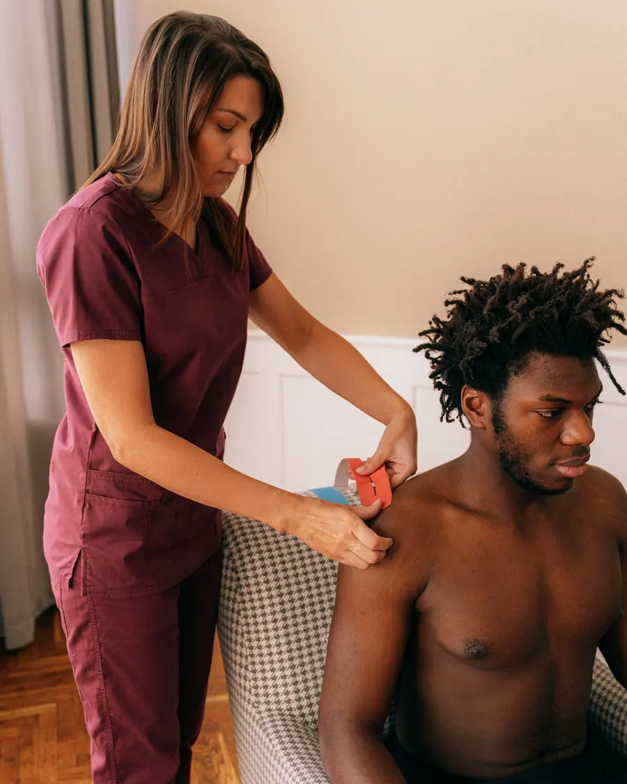 A physiotherapist works on a seated man’s shoulder