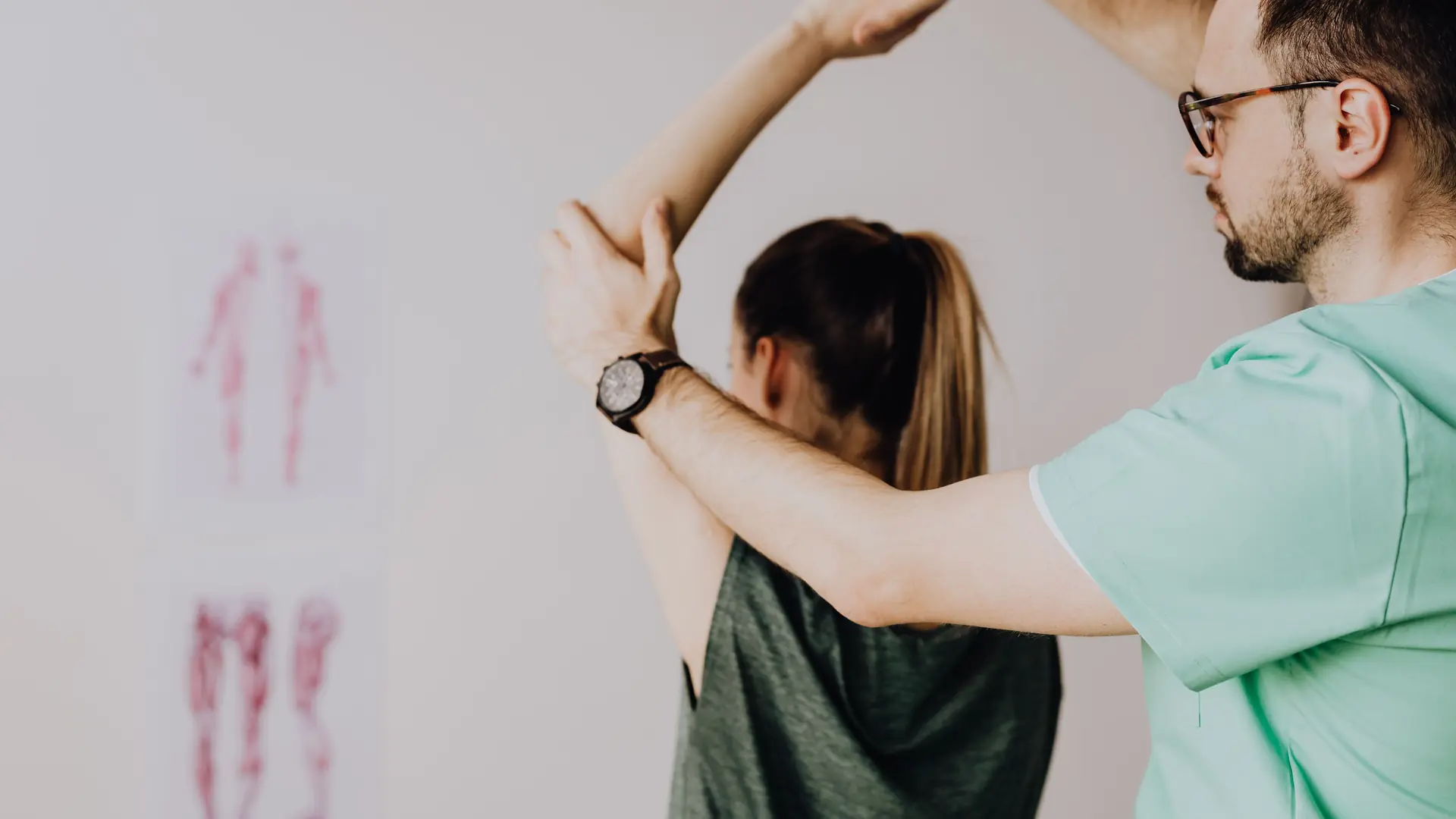 A physiotherapist guides a patient’s arm up and behind her head