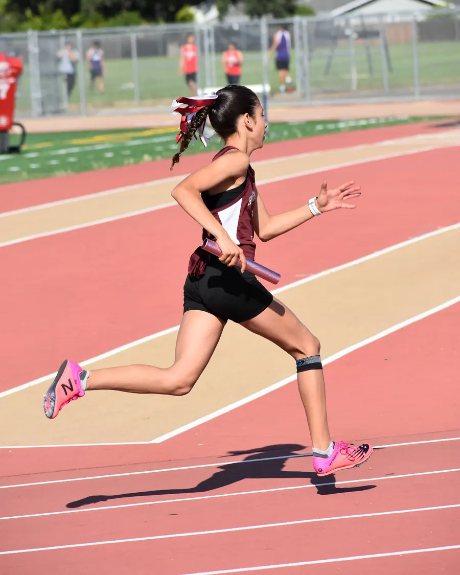 A young runner sprints down a red track