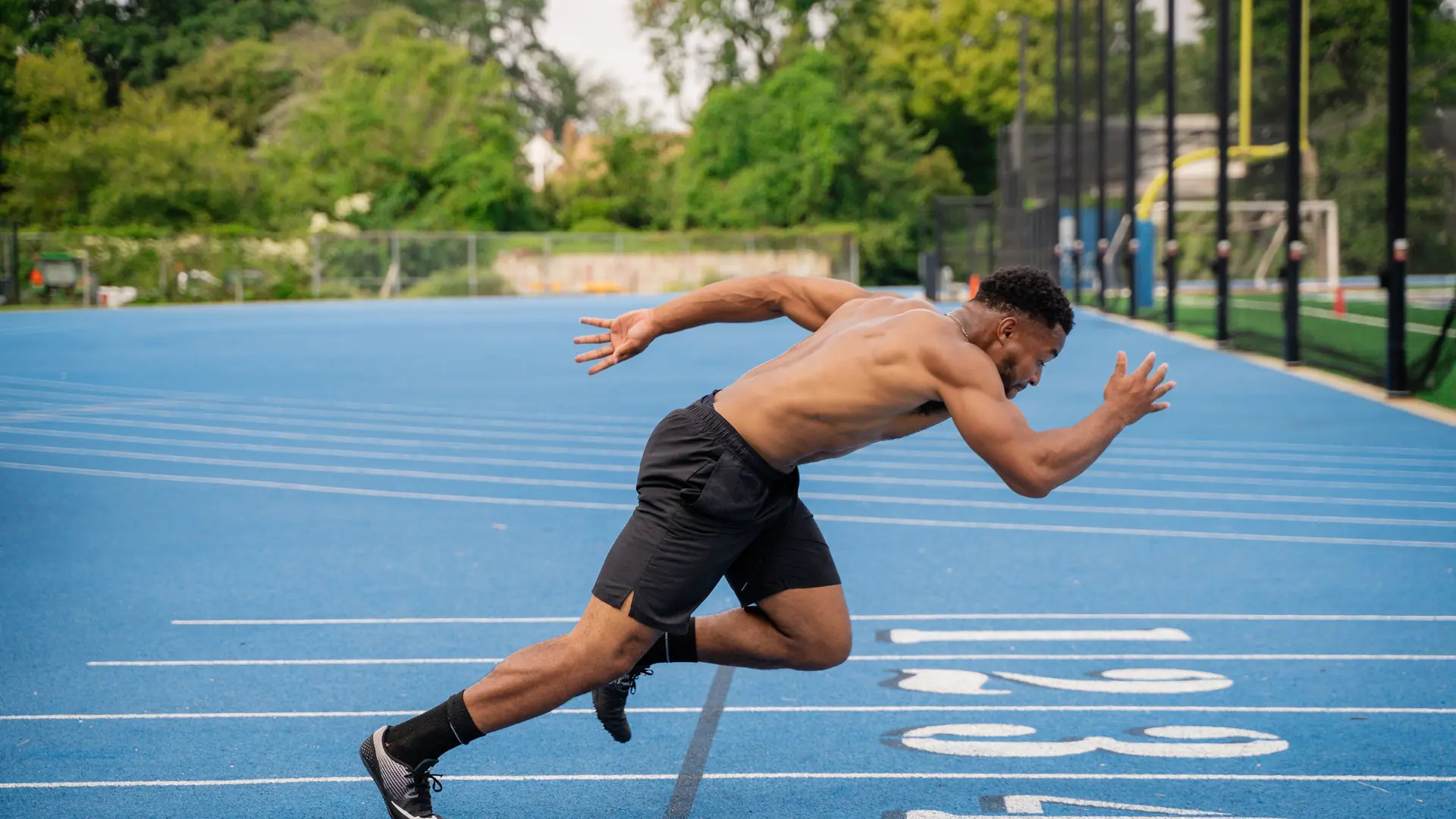 A sprinter drives off the blocks on a blue track