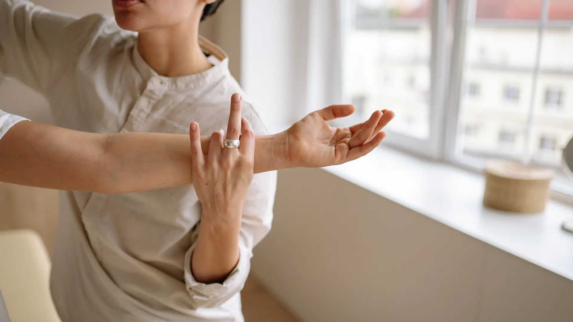 A physiotherapist holds a patient’s wrist by a window